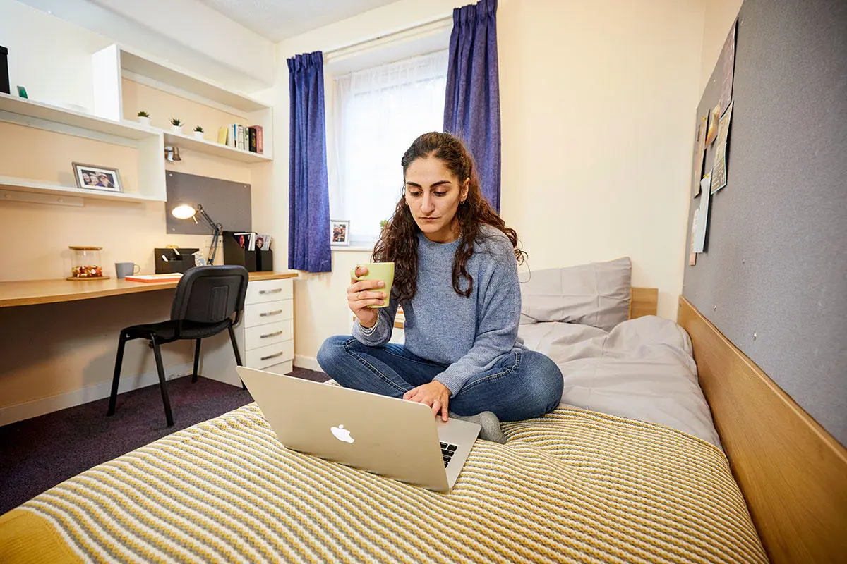 Solent student sat on her bed with her laptop
