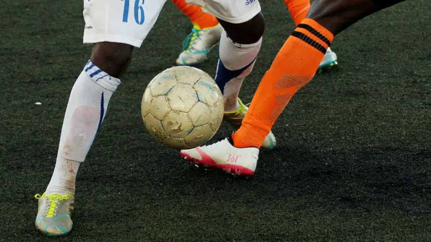 Opposing footballers tackling each other to get the ball
