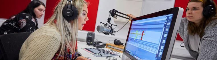 A journalism student sat in front of a camera and behind a green screen