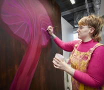 A woman wearing a pink top painting a pink jellyfish