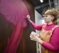 A woman wearing a pink top painting a pink jellyfish