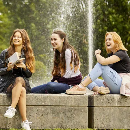 Three students sat near a fountain