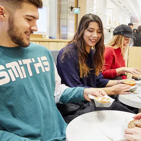 A group of students smiling and eating doughnuts