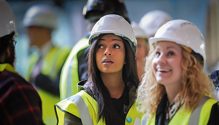 Construction students wearing hard hats and hi-vis jackets