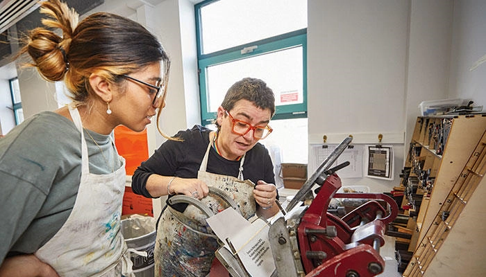 An illustration student using equipment with a technician