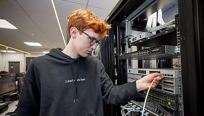 A computer networking student working with machinery