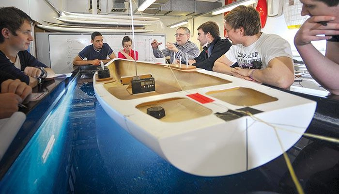 Yacht design students with a model of a yacht hull
