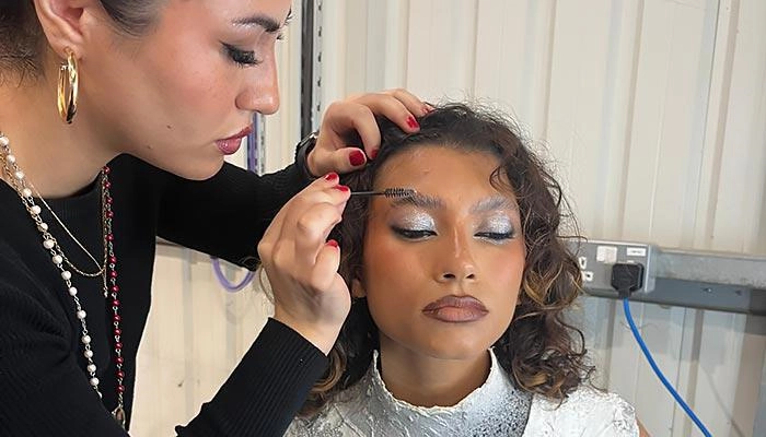 A hair and make-up student applying eye make-up to a model