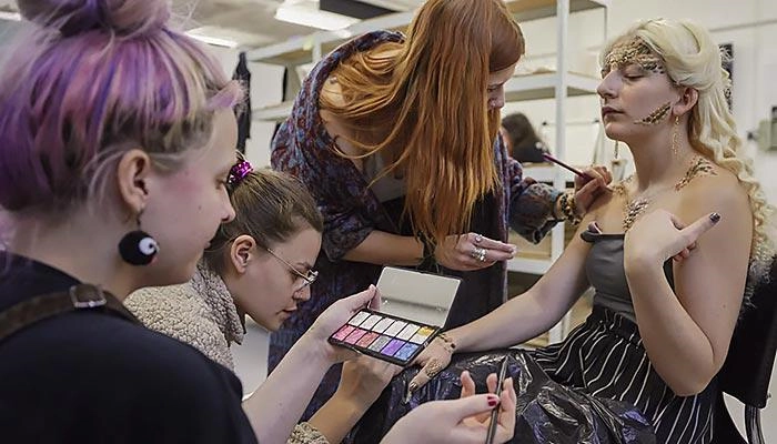 Prosthetics students applying make up to a model