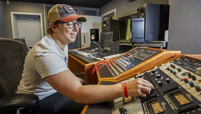 A student using the mixing desk in the music production studio