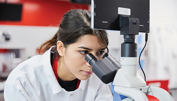 A biomedical science student looking into a microscope
