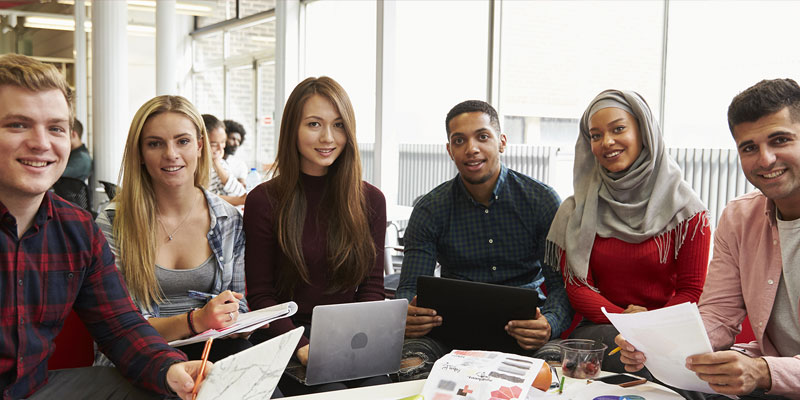 A group of students in the library smiling at the camera