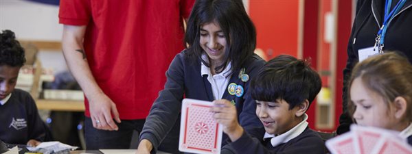 A group of school children holding playing cards as part of an activity