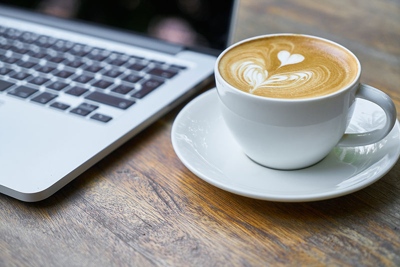 A cup of coffee next to a laptop