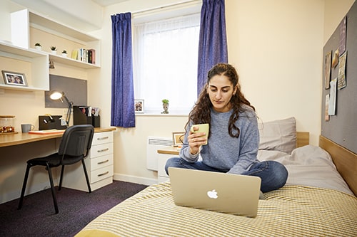 Picture shows girl sitting on bed at Solent halls of residence