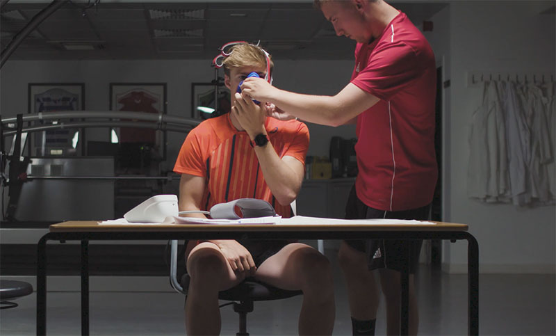 A sports person wearing a VO2 max mask, and a student