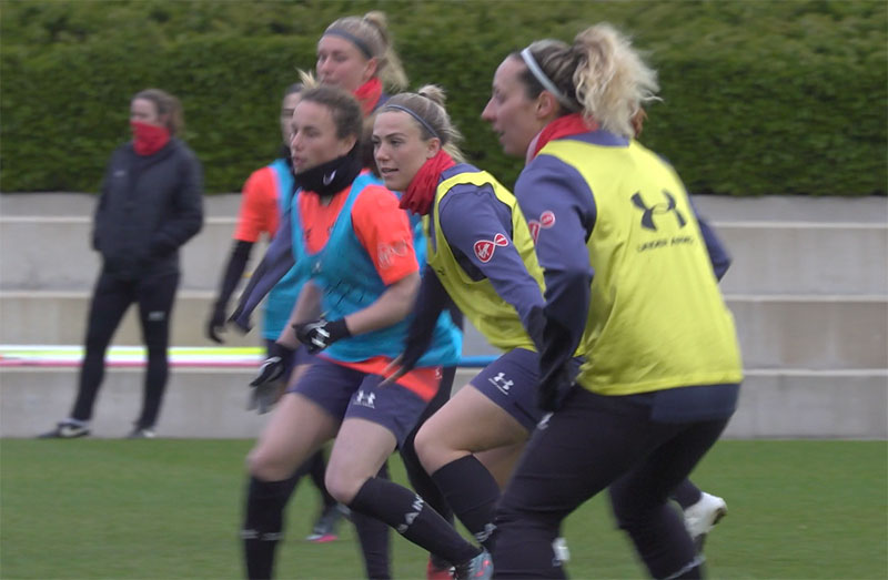 A group of women wearing tabards, playing football