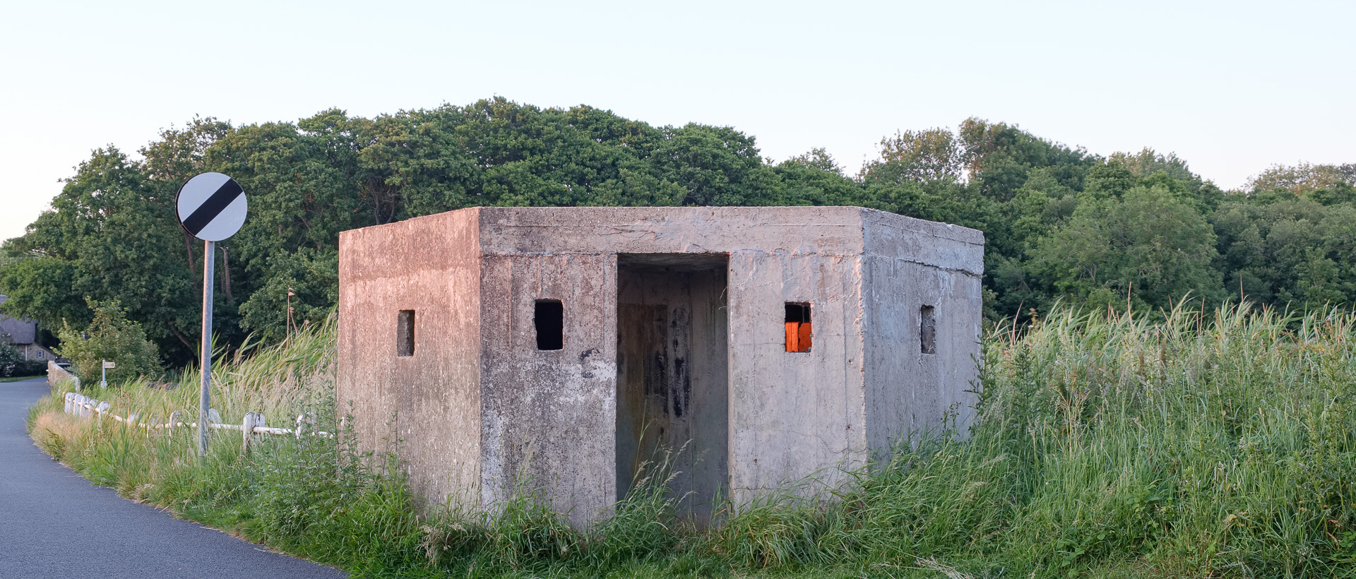 A small hut and road sign at dusk