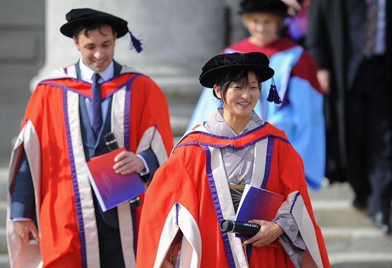 Two PhD graduates wearing robes