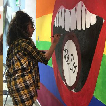 A female student painting a mural of lips outside the Re:So store