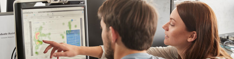 Two students looking at work on a computer screen