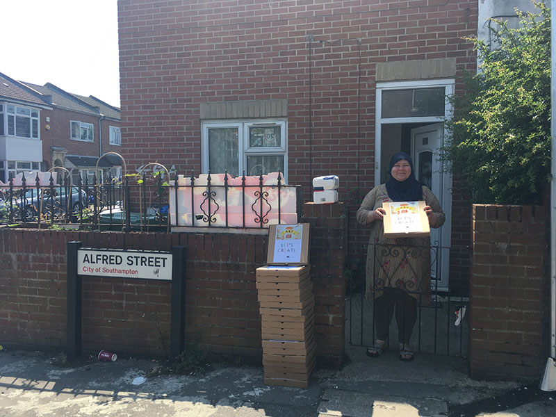 A woman holding one of the pizza boxes