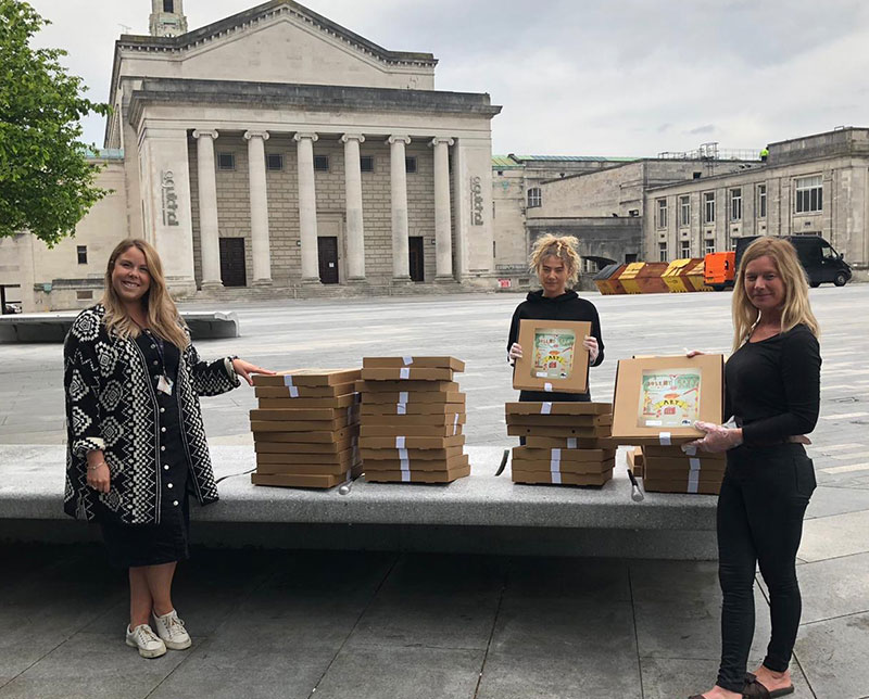 Three women with stacks of art to go pizza boxes outside Southampton Guildhall