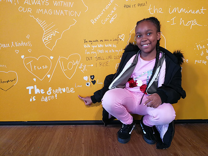 A child pointing to some words on a wall