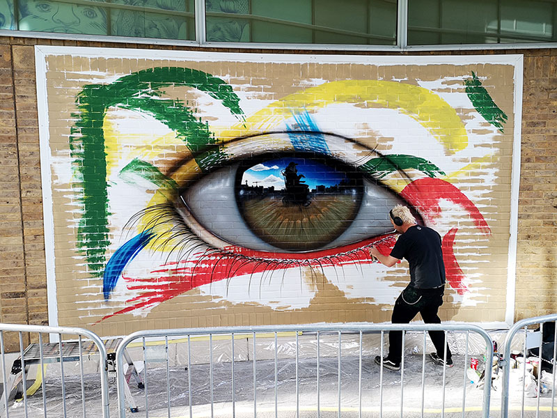 A person painting a large eye on a wall