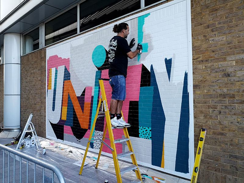 A person painting the word 'unity' on a wall