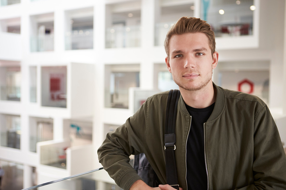 A male student wearing a green jacket looking at the camera