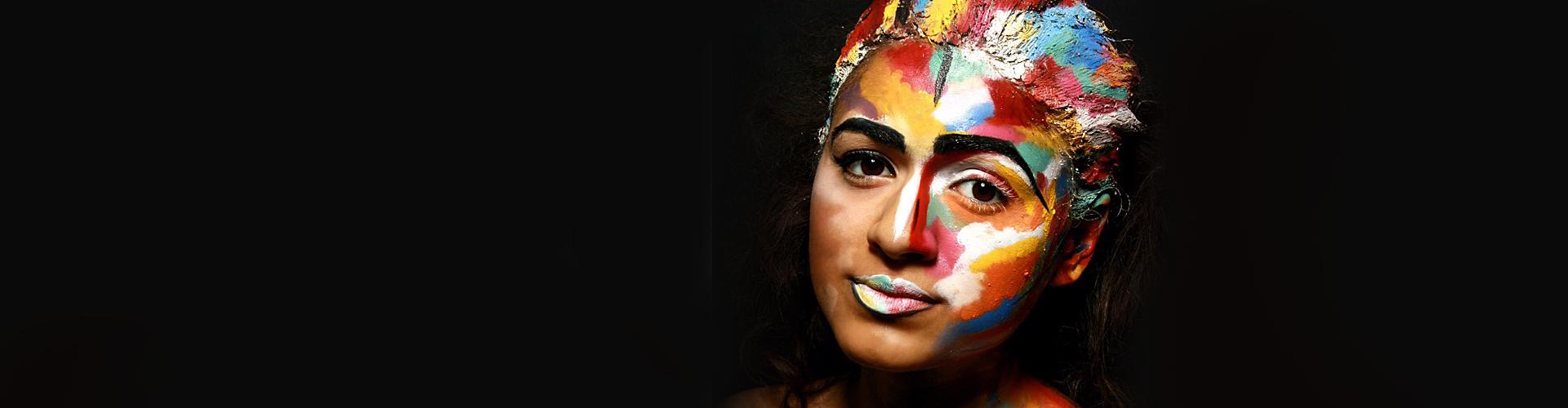 A woman covered in multi-coloured paint.