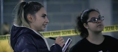 Two criminology students taking notes at a mock crime scene